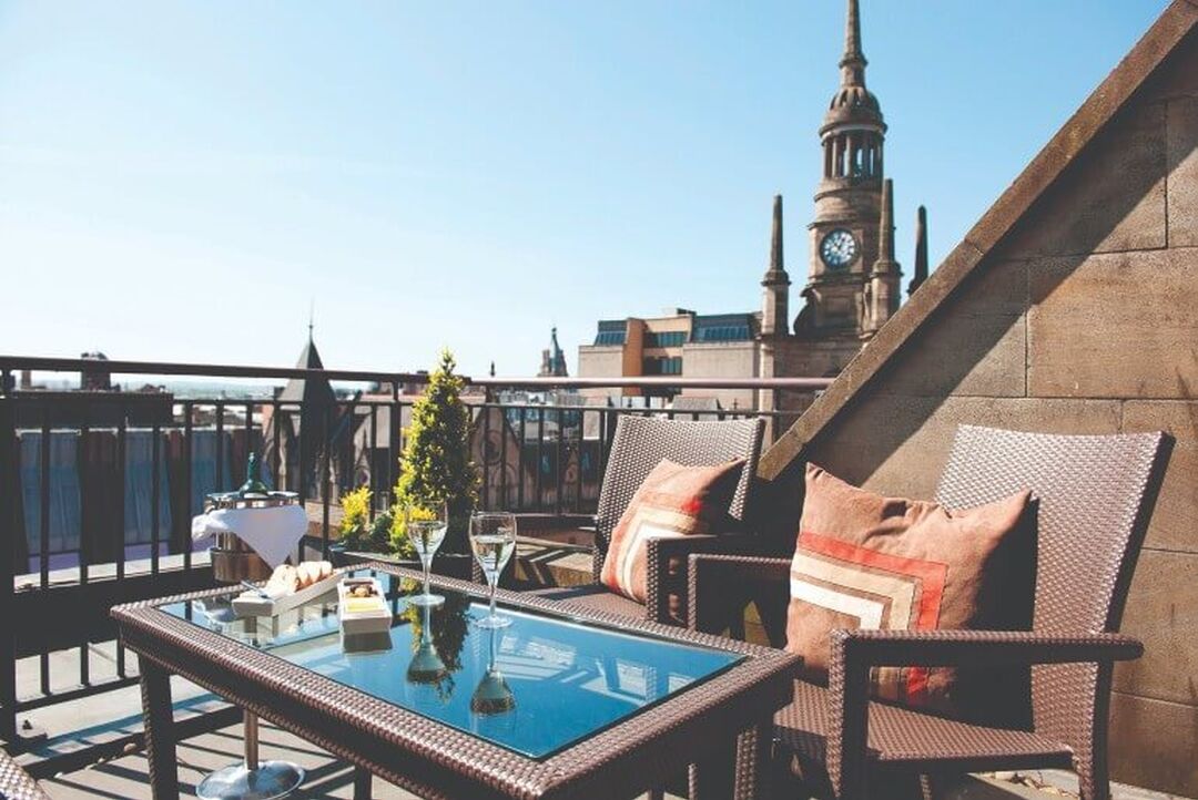 A table on a balcony overlooking a rooftop view of the city centre of Glasgow including the Tron Church steeple.