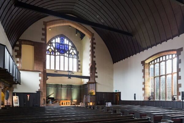 Sunlight floods in through the stained glass window across the pews in Mackintosh Queen's Cross Church.