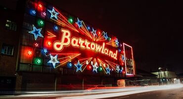 The exterior of Glasgow's Barrowland Ballroom music venue. There is a lit-up sign with the word 'Barrowland' and stars surrounding.