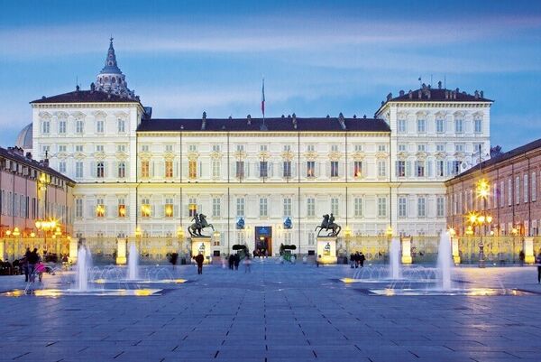 The Royal Palace in Torino, a grand light coloured building with water fountains in front.