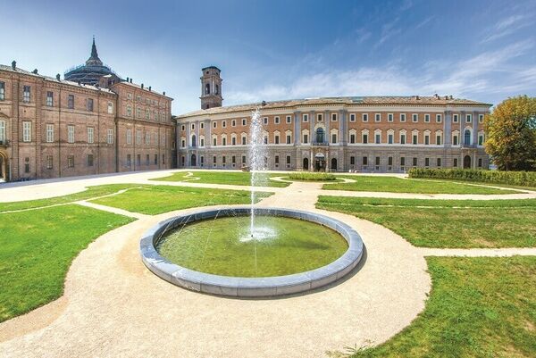 Royal Gardens in Torino with a grand building, grassed area and water fountain.