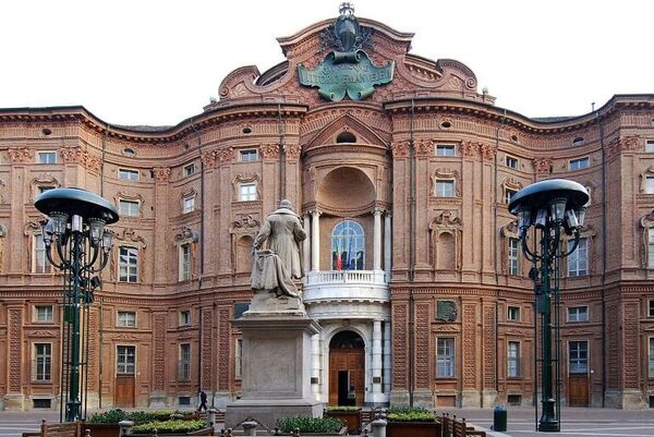 Palazzo Carignano in Torino, a grand building with lampposts and a statue in front.