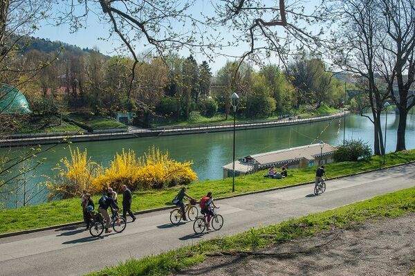 Valentino Park and Po River in Torino, with cyclists and walkers enjoying the outdoors.