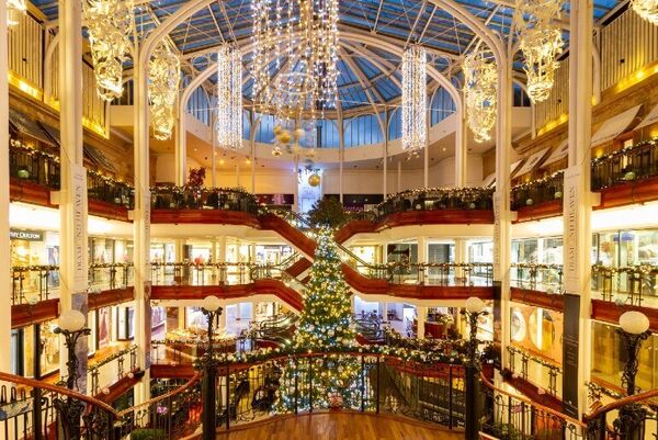 The atrium of Princes Square is lit up with Christmas lights. A tree is the centrepiece with lights also hanging from the glass domed ceiling.