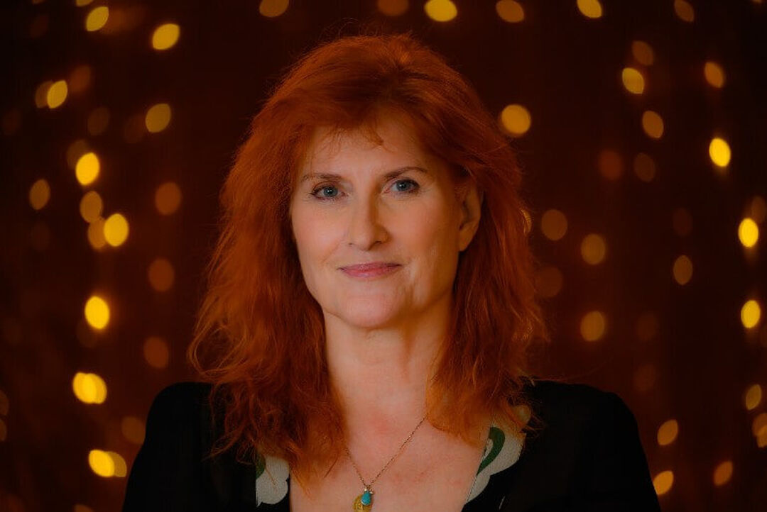 Eddi Reader smiles gently at the camera surrounded by twinkling fairylights.