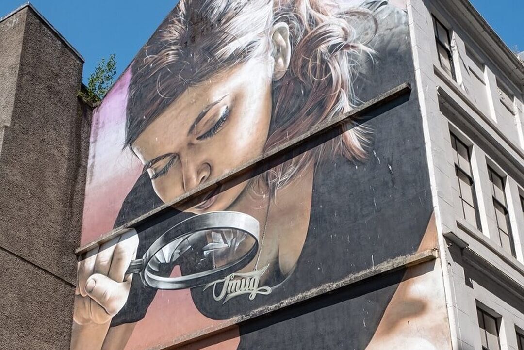 Honey, I Shrunk the Kids mural by artist Smug, depicting a girl holding a magnifying glass.