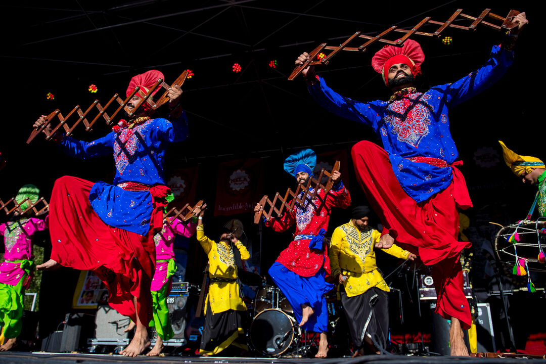 People dancing on a stage in colourful clothing.