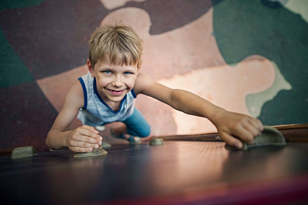 View from above as young boy climbs a climbing wall.