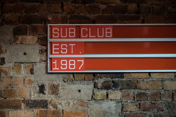 Red sign against a brick wall reading 'Sub Club Est 1987'.