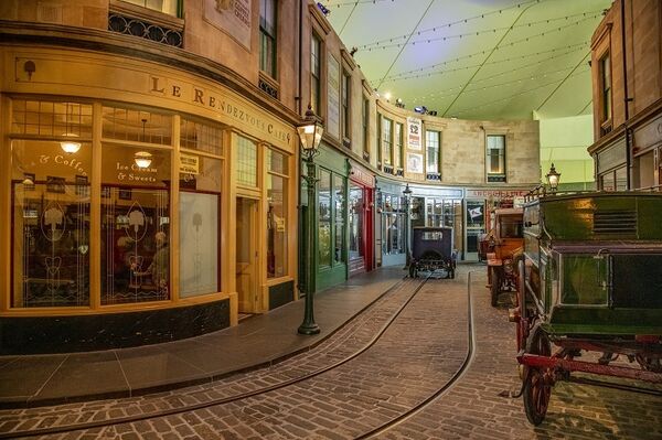 The interior of the Riverside Museum. A Victorian cobbled street with shops, lampposts and cars.