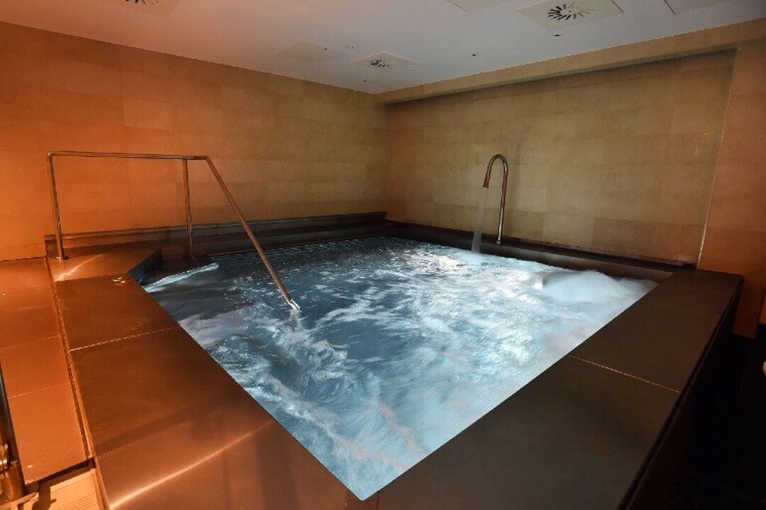 A square jacuzzi is bubbling in a dimly lit room.