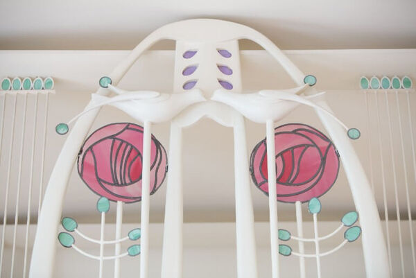 A close up of a Mackintosh Art Nouveau designed piece of furniture. It has a white arch with 2 white doves and 2 pink roses.
