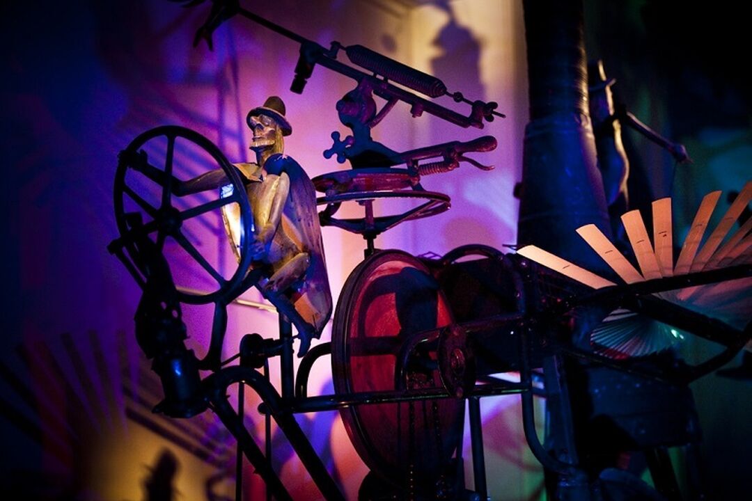 A figure made out of scrap metal steering a wheel is the centrepiece of scrap metal scene, which is all illuminated with purple lighting.
