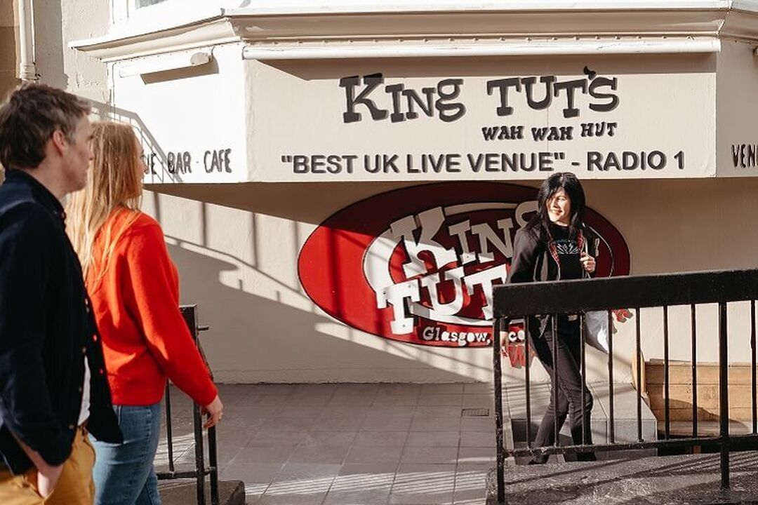 Two people enjoying a Glasgow Music City Tour outside of King Tut's Wah Wah Hut in Glasgow.