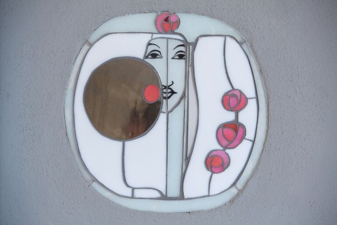 A mirrored wall motif of a women's face and roses that is in the Mackintosh Art Nouveau style