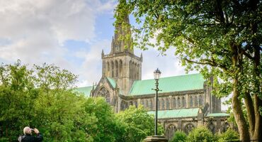 The steeple of Glasgow Cathedral alongside the green copper roof is seen between trees