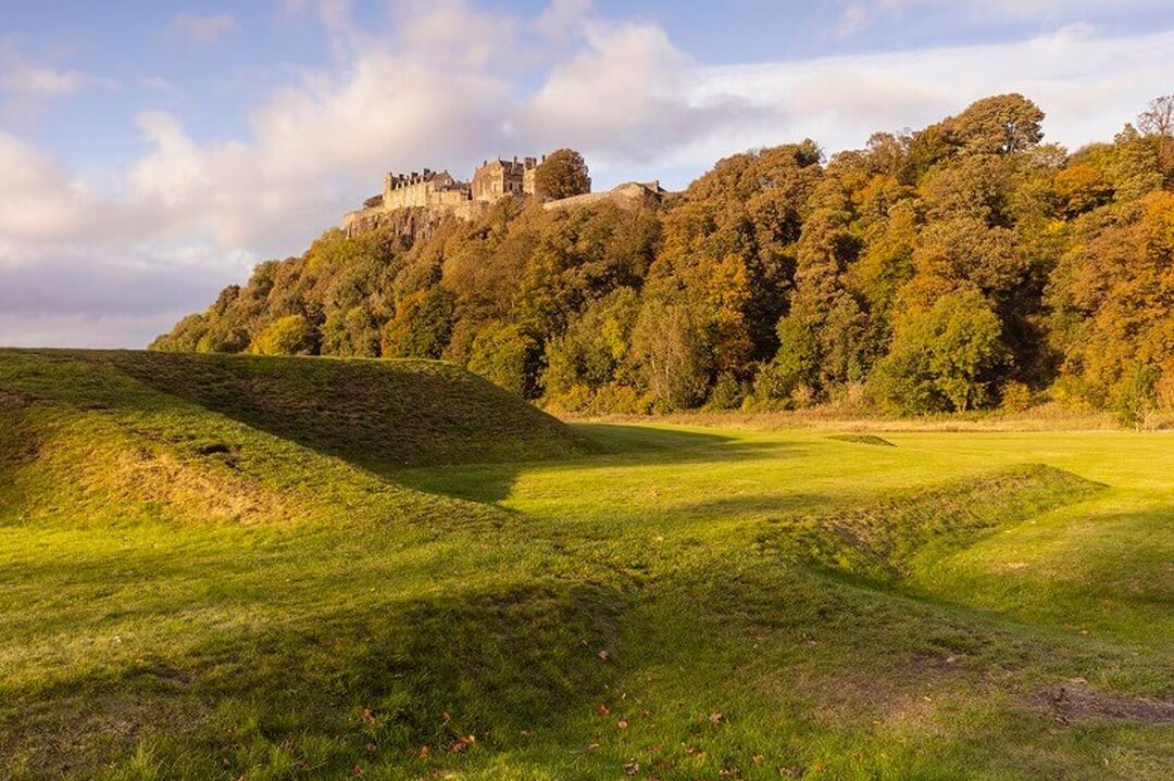 A view of Stirling Castle on a fair weather day with greenery surrounding.