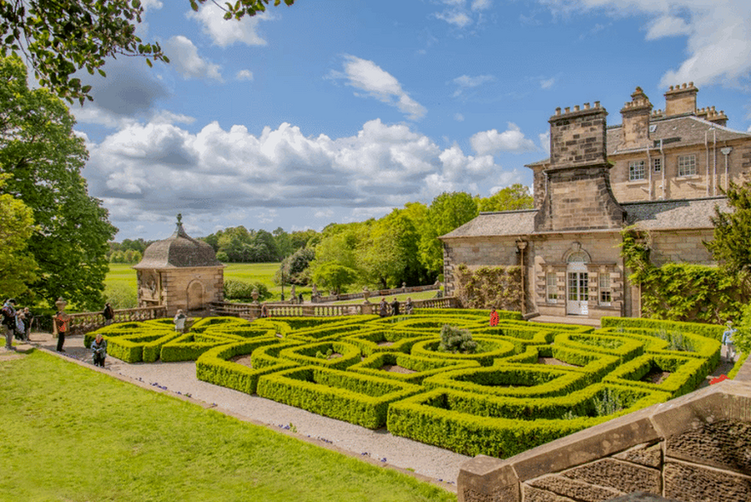An image of Pollok House and the mini maze garden, it's a beautiful sunny day.